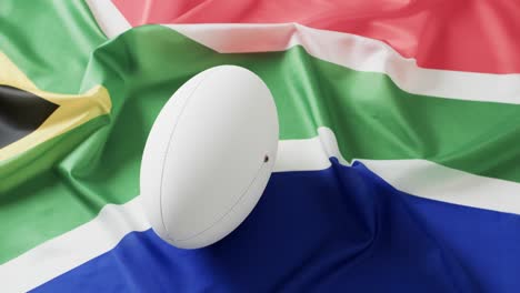 white rugby ball over flag of south africa with copy space, in slow motion