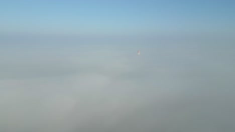 Chimney of a power station in Poland barely visible through thick morning fog under a clear sky