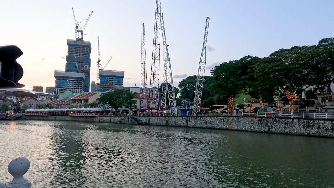 Smooth daylight pan along Singapore riverfront, construction cranes, waterfront buildings, and modern bridge visible