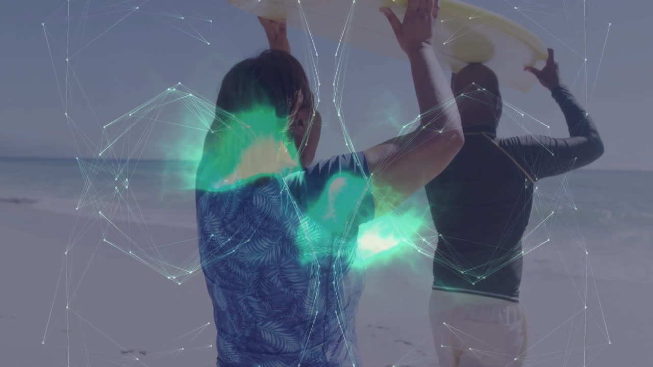Couple carrying surfboard on sandy beach while green network overlay illustrating technology