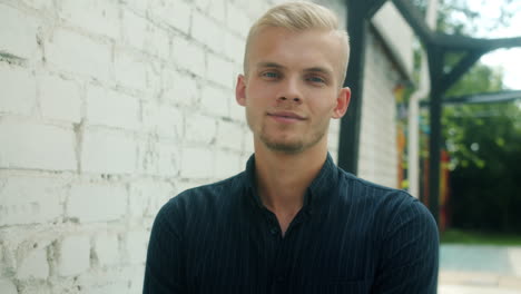 young man posing outside a brick wall
