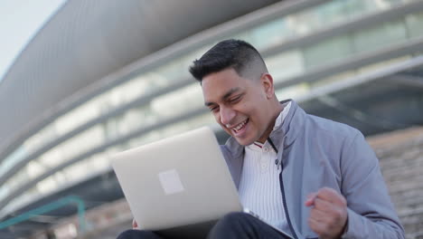 un joven guapo sonriente usando una computadora portátil