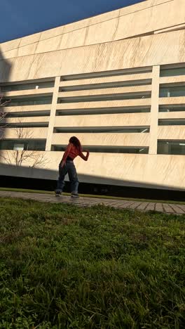 young woman dancing outside a modern building