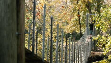 Girl-in-a-warm-cozy-jacket-walks-across-a-suspension-bridge-during-the-autumn-season-and-explores