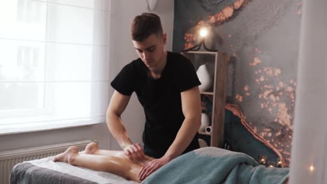 close-up of a man's masseur's hands massaging a woman's legs on a massage table