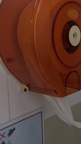 persona que demuestra cómo usar un dispensador de toallas de mano