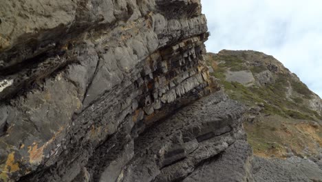 tectonic volcaninc plates in the beach of gruta da adraga in portugal with mountain in background