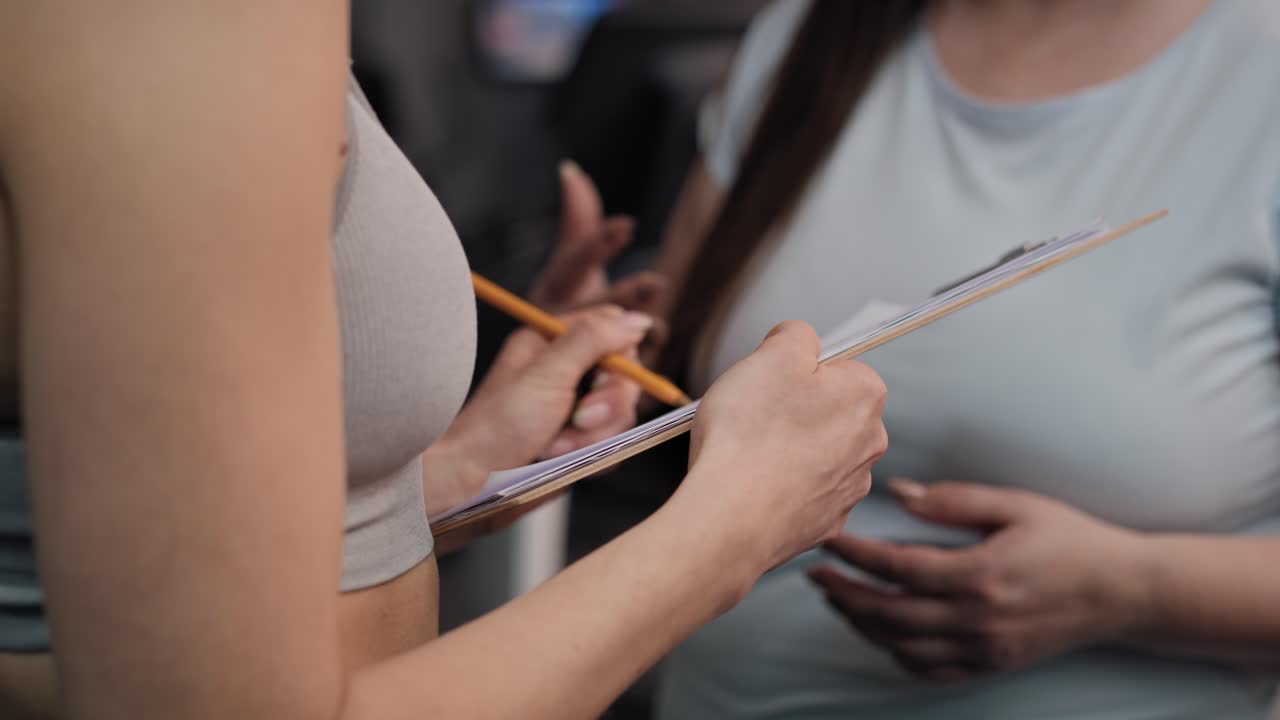 체중이 많은 여성이 체육관에서 여성 트레이너와 대화하는 클로즈업입니다.