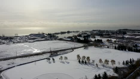 drone volando hacia la orilla del lago en mississauga de un lago ontario congelado y nevado