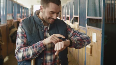 man is using a smart watch in stable.