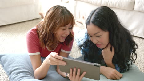 two young biracial female friends are sharing a joyful moment with a tablet