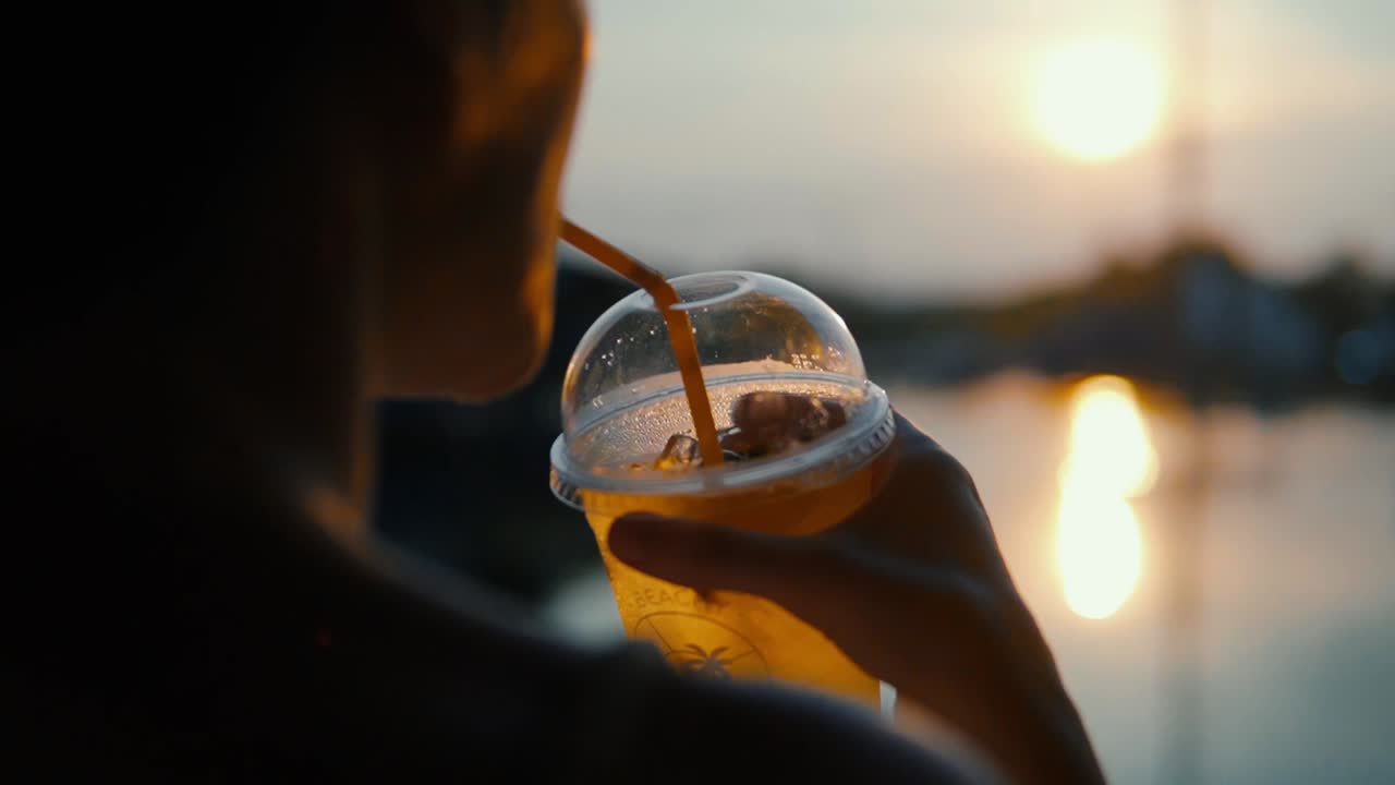 mujer bebiendo una refrescante bebida de té helado al atardecer