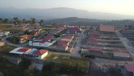4k drone shot of a truck leaving a construction site in central america with houses and a residential