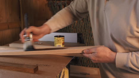 close up footage of man staining plank of wood in a wood workshop