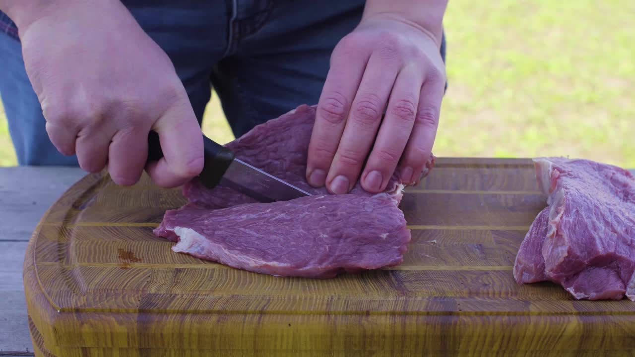 손은 밖의 나무 표면에 칼을 사용하여 고기를 잘라