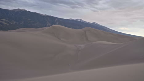 tent set up in middle of sand dunes with mountains in background