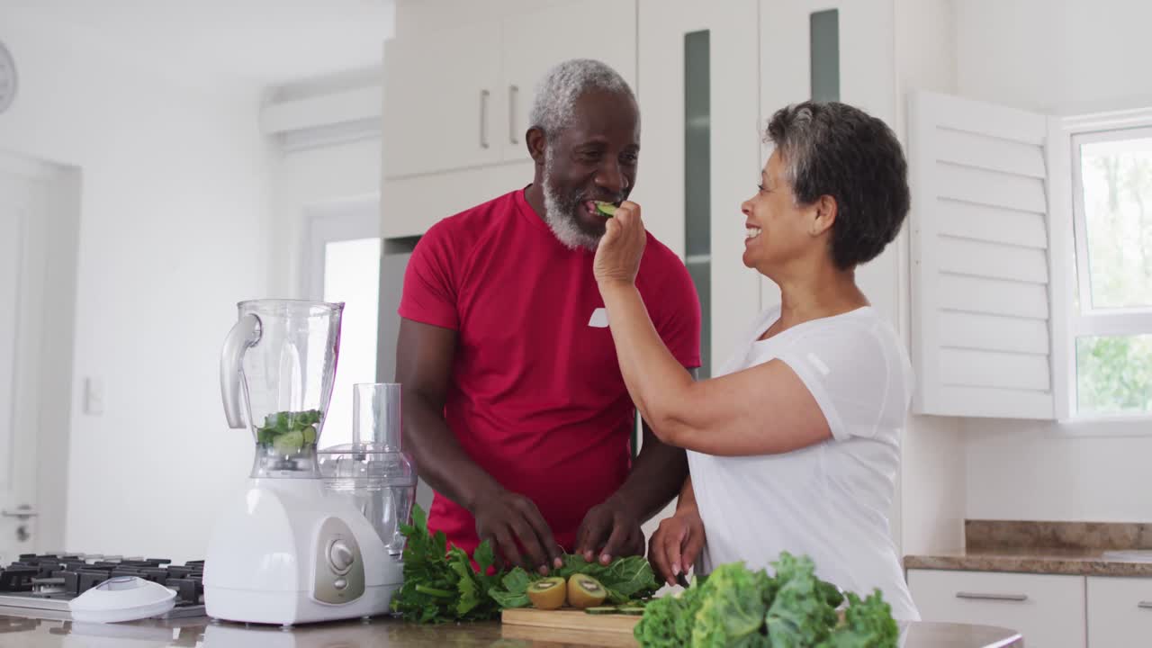 hombre y mujer afroamericanos mayores preparando bebidas saludables de frutas y verduras en casa