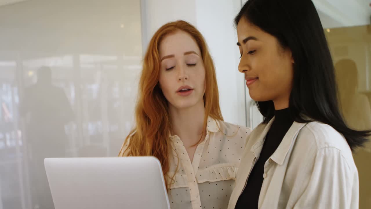 Female executives discussing over laptop 4k