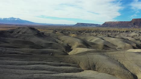 aerial view of man running on barren dry badlands, desert landscape of utah usa