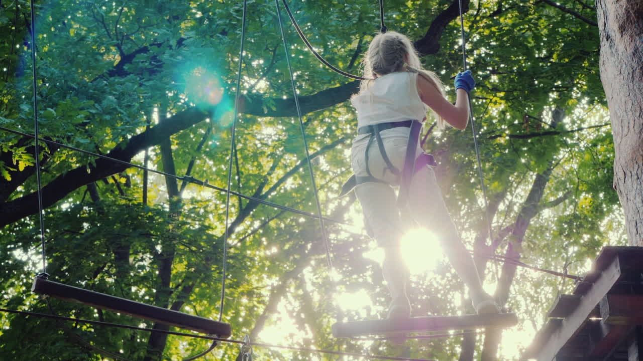 un niño valiente camina por la cuerda floja entre árboles altos infancia activa y diversión