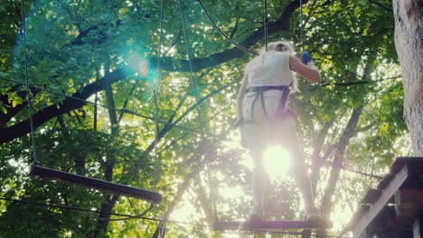 a brave child walks along a tightrope between tall trees active childhood and fun