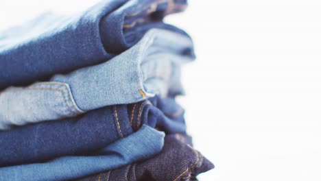 Close-up-of-folded-jeans-with-different-shades-on-white-background-with-copy-space