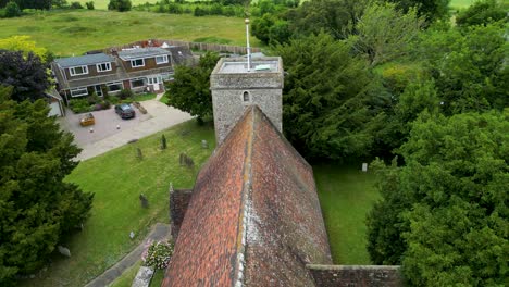 A-push-in-shot-of-St-Margaret-of-Antioch-church-in-Womenswold,-flying-over-the-church-roof-towards-the-tower