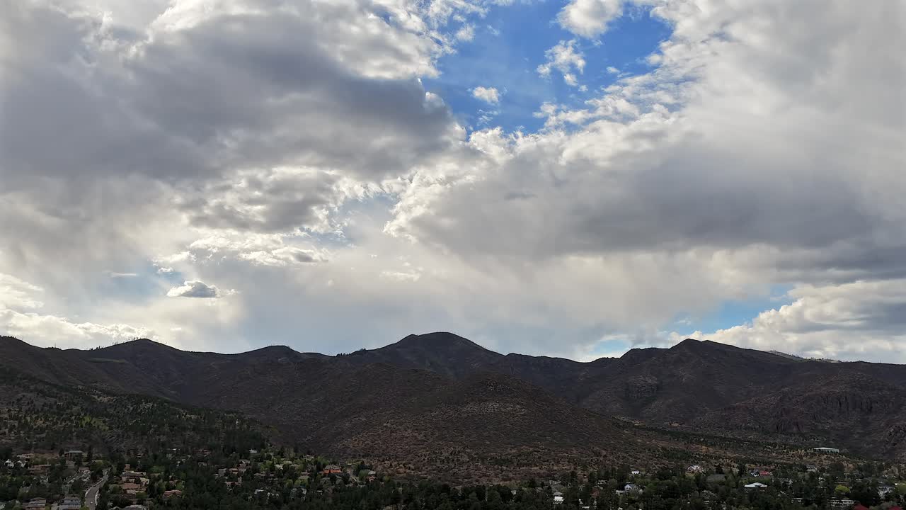A dramatic and ethereal 4K drone timelapse captures stunning sky colors as clouds shift over a southwest mountain range. The vibrant light and motion create an epic backdrop