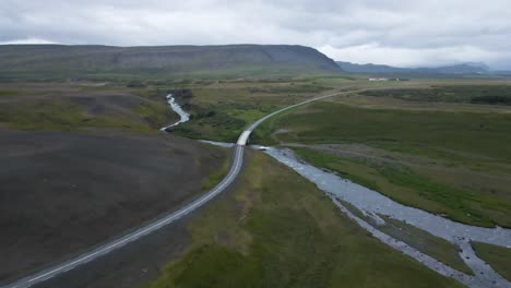 Traverse-Iceland's-scenic-expanses-with-this-captivating-4K-drone-footage,-featuring-a-unique-perspective-as-a-car-drives-over-an-iconic-bridge