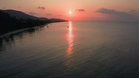 el sol rojo poniéndose más allá del horizonte sobre la tranquila costa del océano tropical en bali