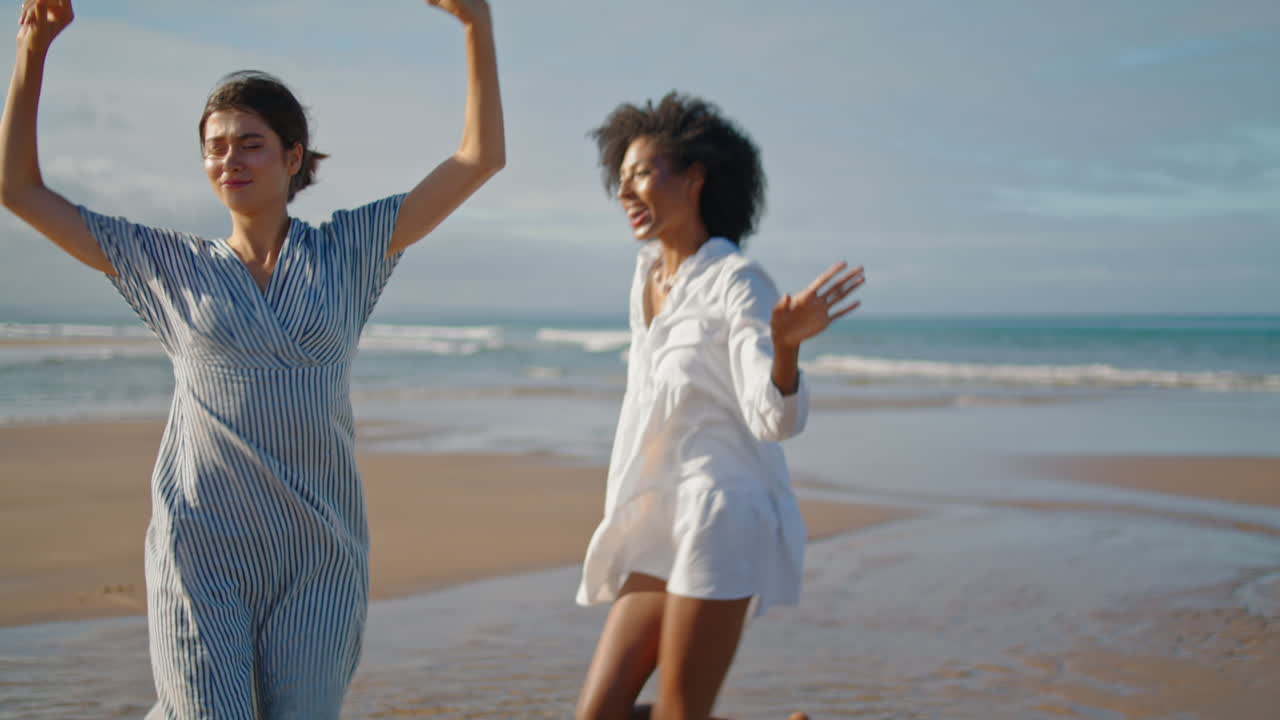 chicas felices bailando en la playa el fin de semana de verano. pareja lgbt emocionada y sonriente disfrutando