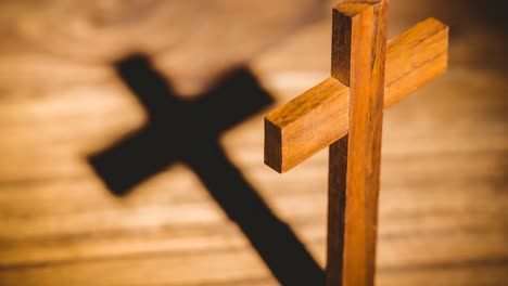 wooden christian cross casting shadow over wooden surface