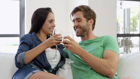 retrato de una pareja joven sentada en el sofá con un vaso de vino rojo