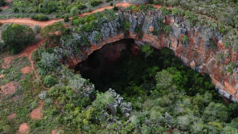 Drone-Aéreo-Inclinándose-Hacia-Abajo-De-La-Gran-Entrada-De-La-Cueva-Lapa-Doce-De-Rocas-Coloridas-Con-Una-Selva-Tropical-Autónoma-Debajo-En-El-Parque-Nacional-Chapada-Diamantina-En-Bahia,-Noreste-De-Brasil