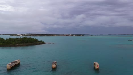 Aerial-view-of-old-bridge-mounts-in-clear-turquoise-water-by-tropical-island