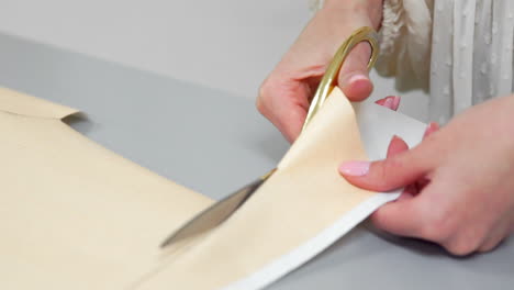 joven diseñadora con cinta en el cuello de pie en el estudio de costura y dibujando líneas con tiza y regla. modista en el atelier cortando un patrón para la ropa futura.