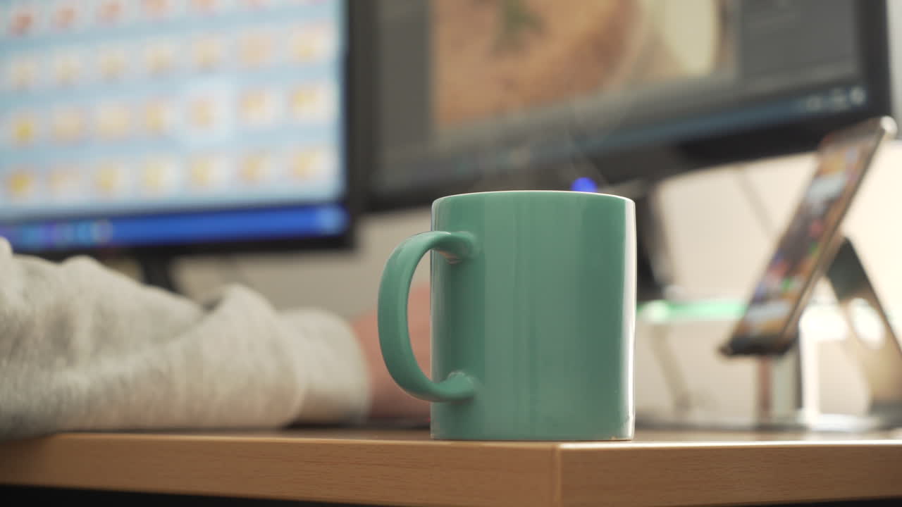 Steaming Teal Mug on a Desk with Computer and Phone