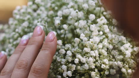 Woman-with-gold-ring-strokes-gentle-bouquet-of-gypsophila