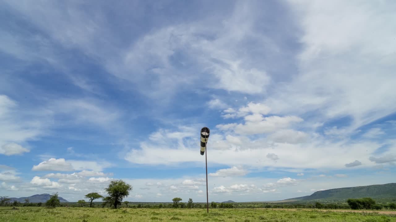 A black and white windsock fluttering in the breeze at a remote bush airstrip in Kenya's iconic Maasai Mara.