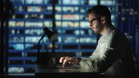 Retrato-De-Un-Hombre-De-Negocios-Exitoso-Y-Reflexivo-Que-Trabaja-En-Una-Computadora-Portátil-En-Su-Oficina-De-La-Gran-Ciudad-Por-La-Noche.-Carismático-Emprendedor-Digital-Realiza-Análisis-De-Datos-Para-Estrategia-De-Comercio-Electrónico.