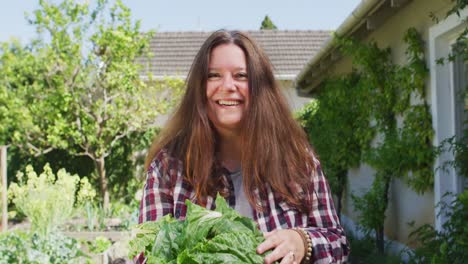 retrato de una mujer caucásica feliz con lechuga en el jardín