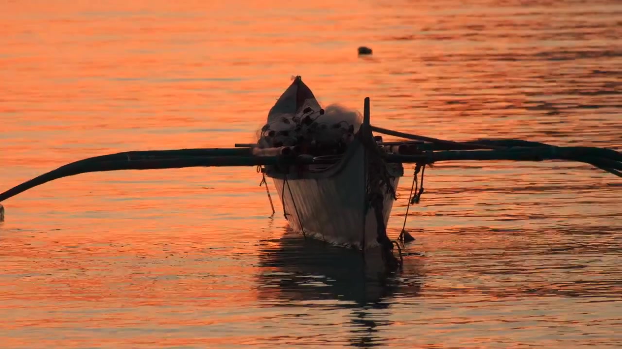 Nærbillede af en traditionel filippinsk bangka-båd, der flyder under tropisk solnedgang.