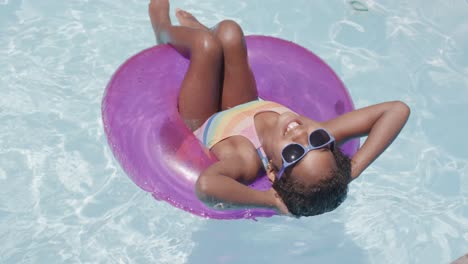 Feliz-Chica-Afroamericana-Sentada-En-Un-Anillo-De-Natación-En-La-Piscina,-Cámara-Lenta