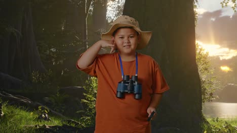 niño asiático con un sombrero y binoculares usando la lupa y luego haciendo el gesto de llamarme mientras explora la naturaleza del bosque. niño investigador examina algo, concepto de aventura de turismo de viaje