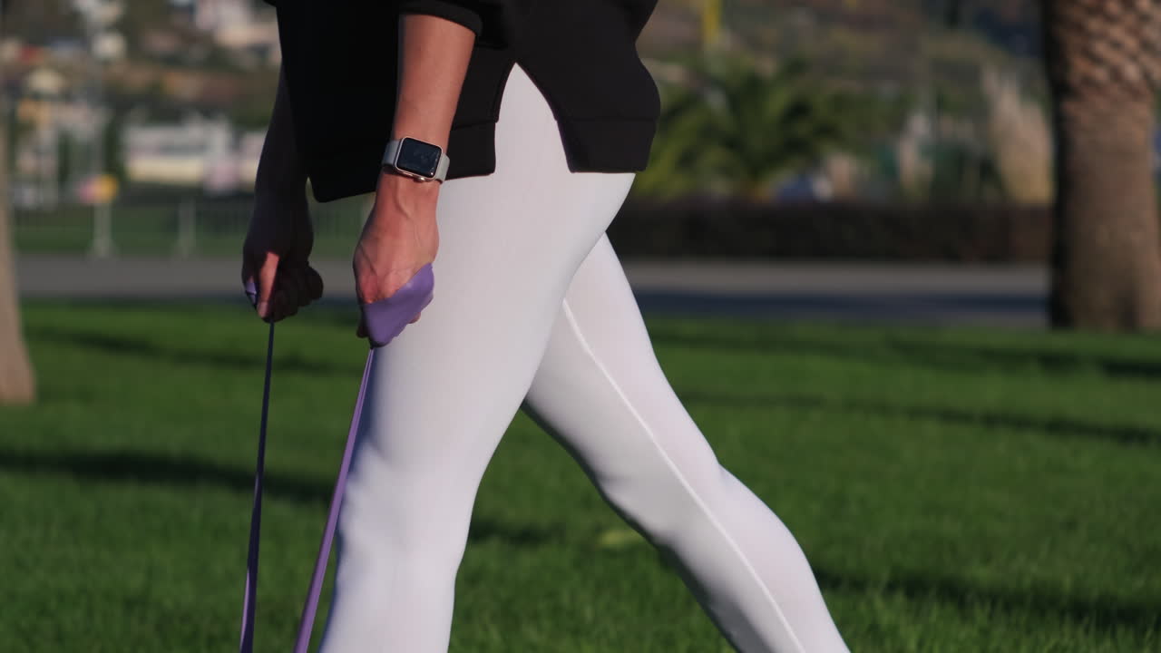 야외에서 저항 밴드로 다리 운동을 하는 여자