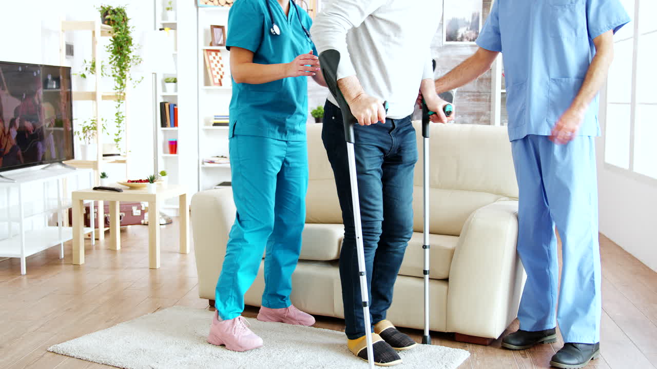 은퇴 가정 의 간호사 들 의 팀 이 장애인 노인 을 소파 에 앉히는 데 도움 을 하고 있다