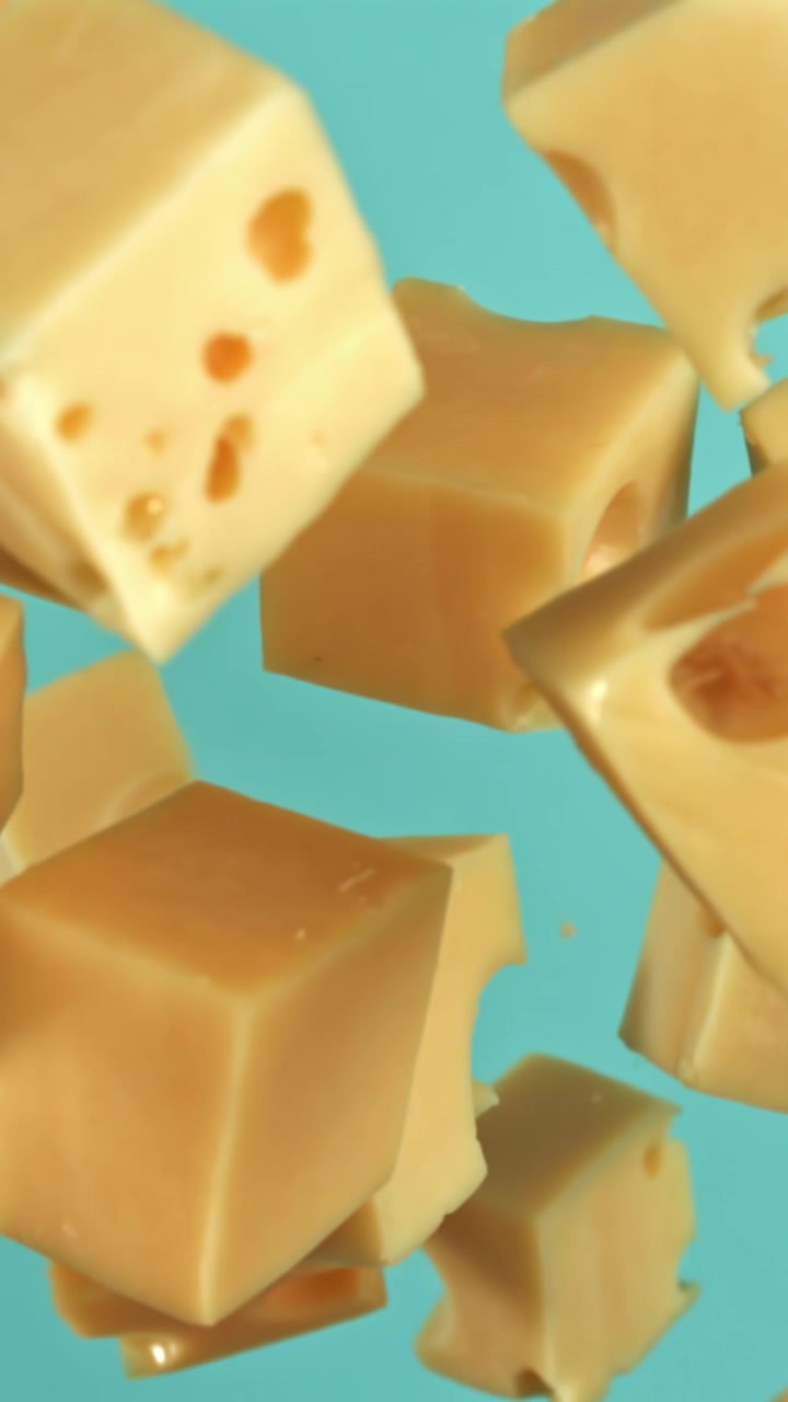 Délicieux cubes de fromage tombant au ralenti sur fond bleu