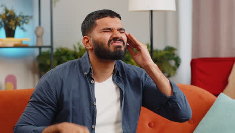 sick ill indian man rubbing temples to cure headache problem suffering from tension migraine stress