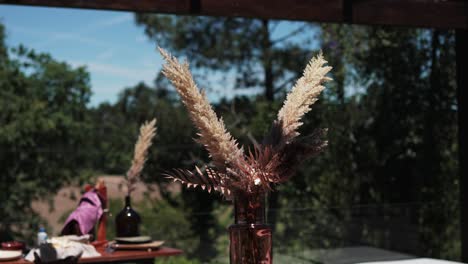 dried floral arrangement in a copper vase decorates an outdoor table under natural light