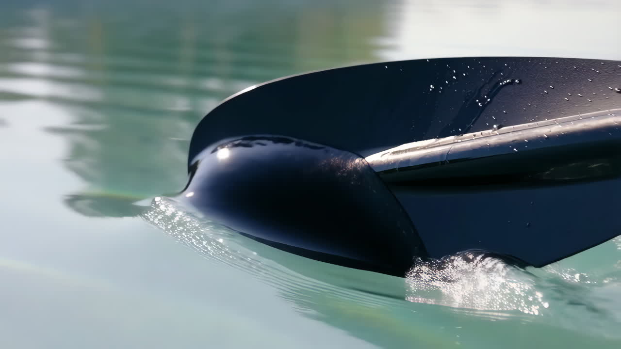 Paddle dipping into clear water, creating splashes and ripples
